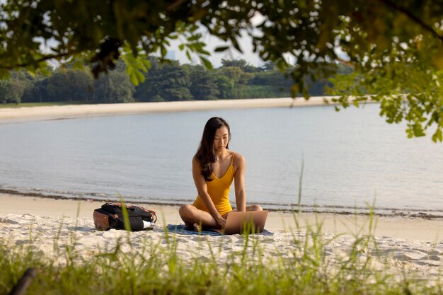 Полный снимок женщина, сидящая на пляже