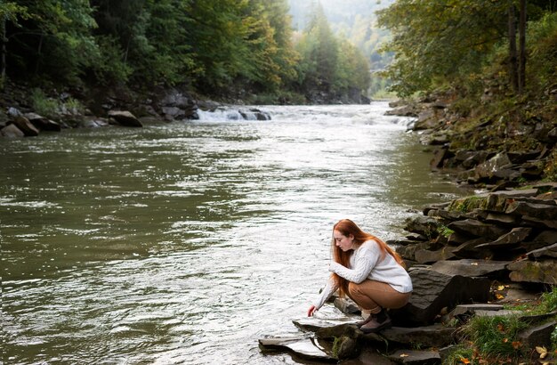 full shot woman sitting by the river