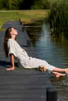 Бесплатное фото Женщина в полный рост, сидящая у озера
