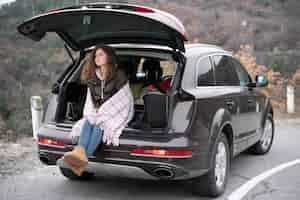 Free photo full shot woman sitting in car trunk