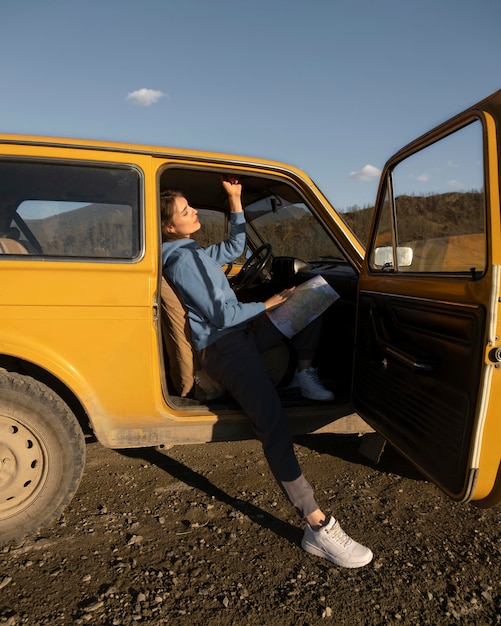 Full shot woman sitting in car with map