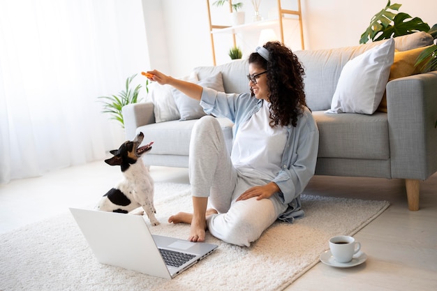 Full shot woman sitting on floor with dog