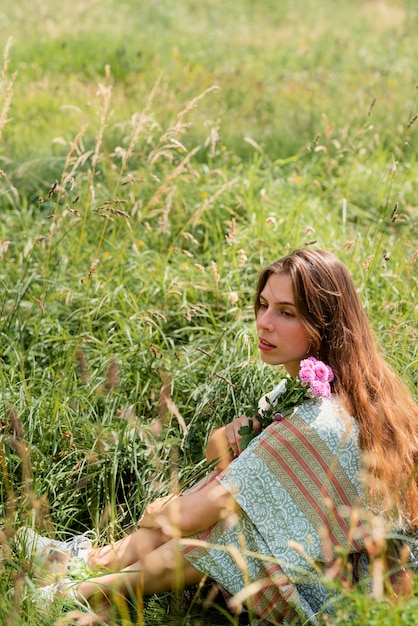 Foto gratuita donna piena del colpo che si siede sull'erba