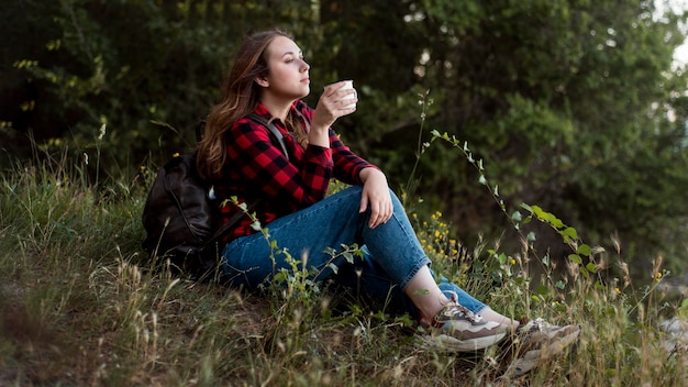 Full shot woman sitting on ground in forest