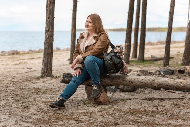 Free photo full shot woman sitting on log