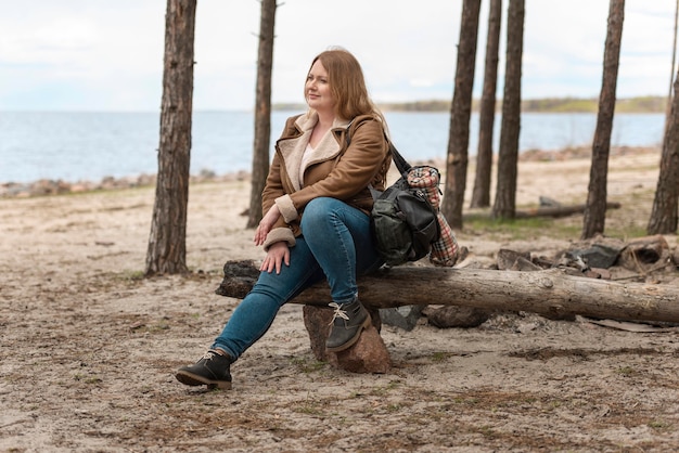 Full shot woman sitting on log