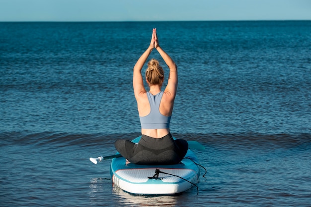 Donna a tutto campo seduta sul paddleboard