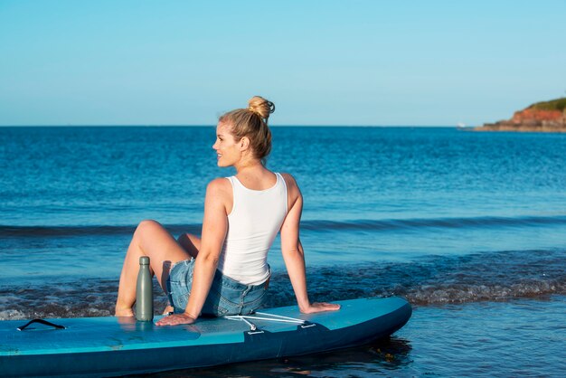 Полный выстрел женщина, сидящая на доске для серфинга