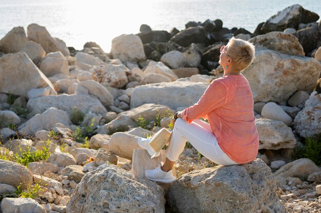 Full shot woman sitting on rock