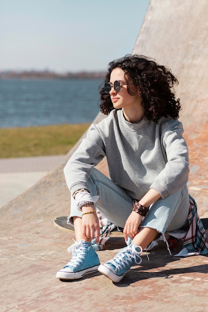 Foto gratuita donna piena del colpo che si siede sullo skateboard