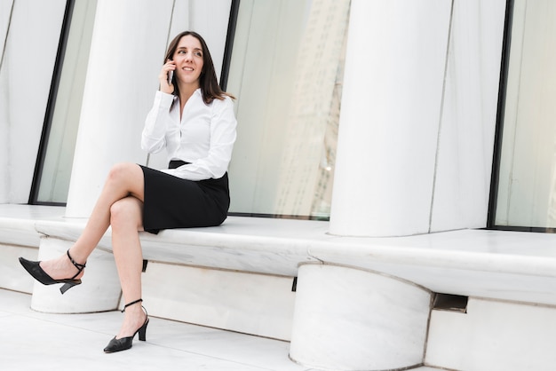 Foto gratuita donna della foto a figura intera che si siede con il telefono