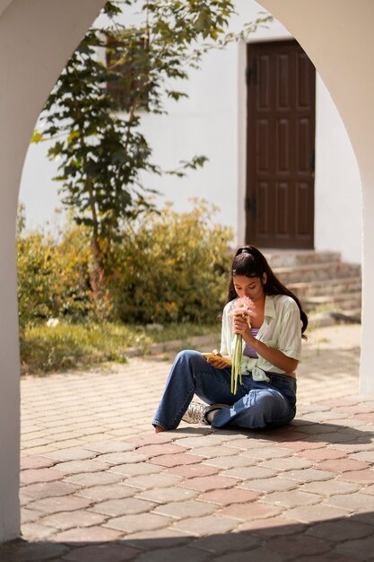 Full shot woman smelling flowers