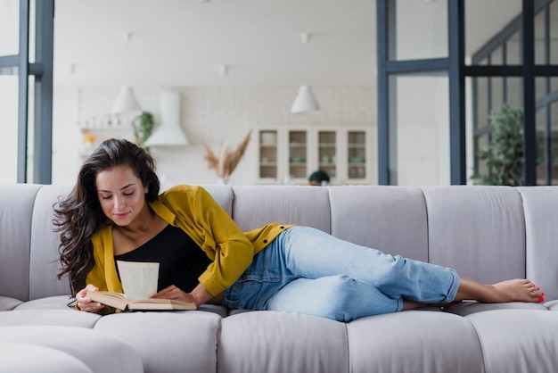 Free photo full shot woman on the sofa reading