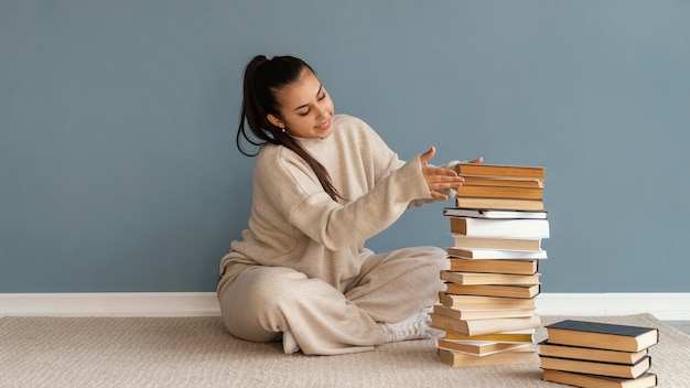 Full shot woman stacking books