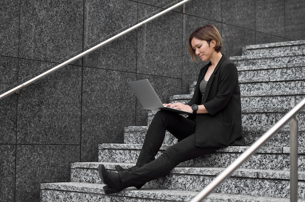 Full shot woman on stairs with laptop