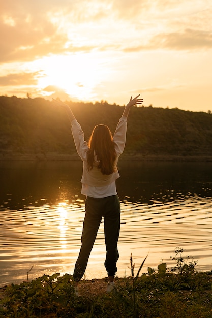 Free photo full shot woman standing by the lake