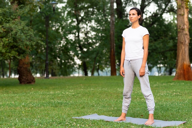 Full shot woman standing on yoga mat