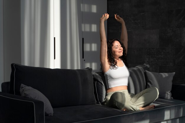Full shot woman stretching on couch