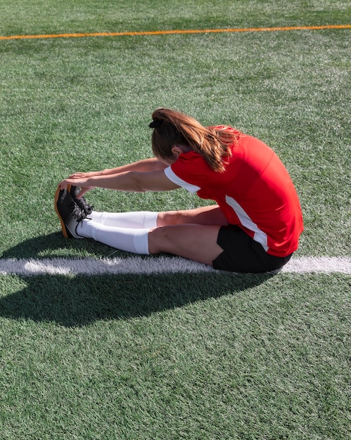 Full shot woman stretching on field