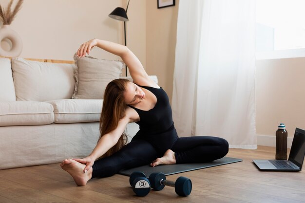 Full shot woman stretching indoors