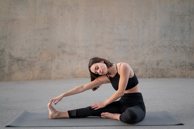 Full shot woman stretching leg on mat