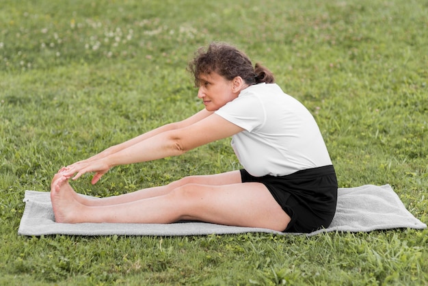 Full shot woman stretching on mat