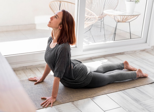 Full shot woman stretching on mat