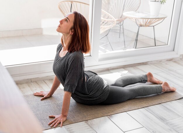 Full shot woman stretching on mat