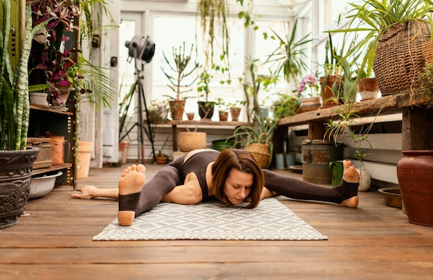 Full shot woman stretching on mat