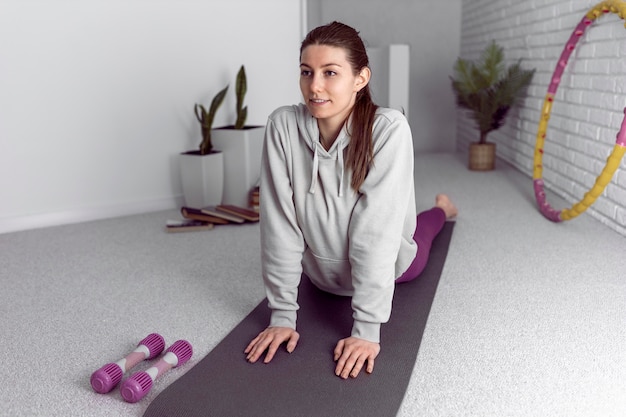 Free photo full shot woman stretching on mat