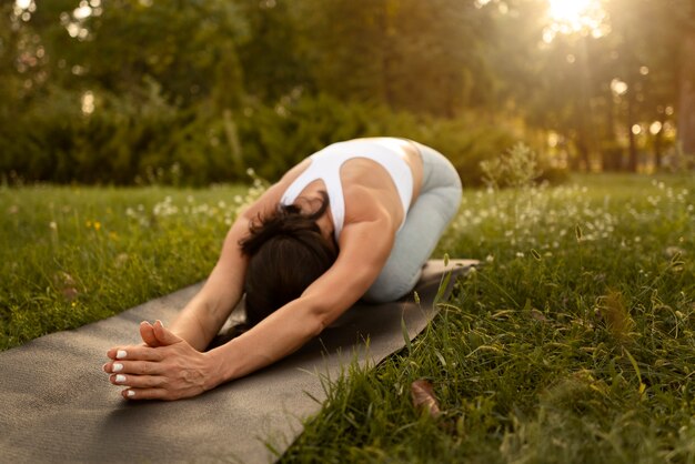 Full shot woman stretching on mat