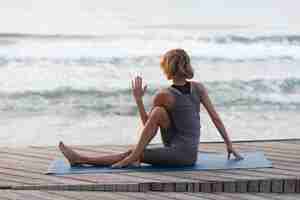 Free photo full shot woman stretching outside near sea