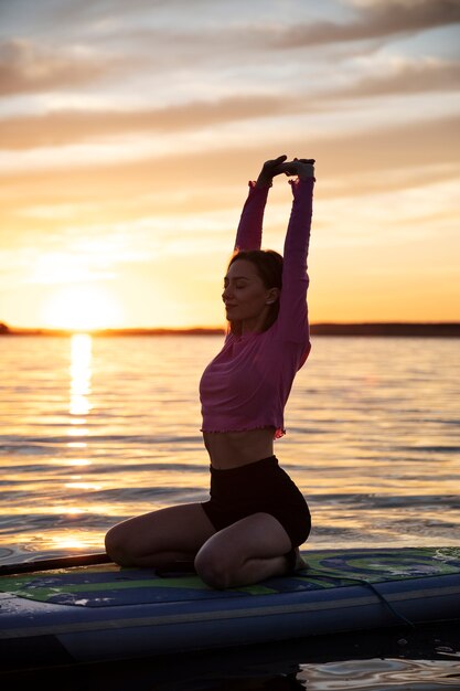 Full shot woman stretching on paddleboard