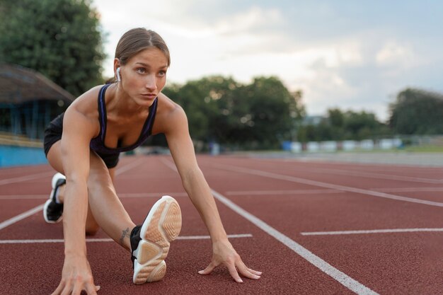 ランニングトラックでストレッチするフルショットの女性