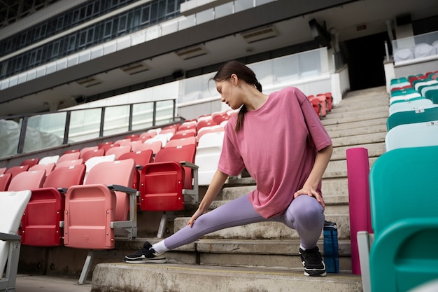 Free photo full shot woman stretching on stairs