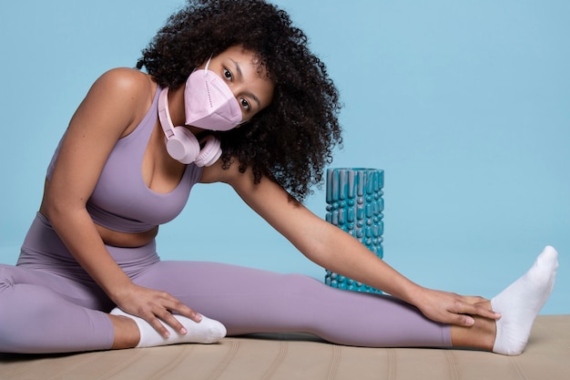 Full shot woman stretching with mask