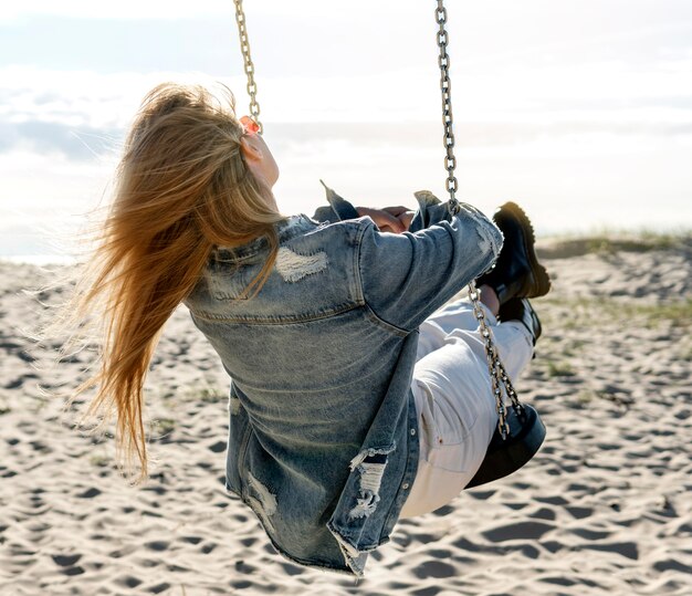 Full shot woman on swing at beach