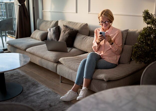 Full shot woman taking a break with smartphone