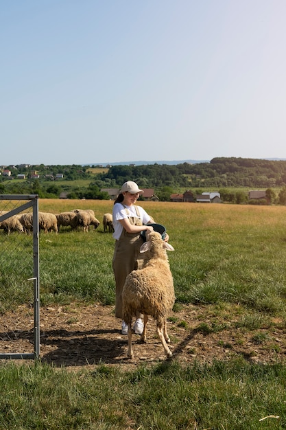 フィールドで羊の世話をするフルショットの女性