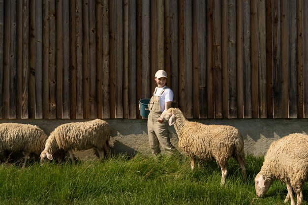 Женщина в полный рост ухаживает за овцами