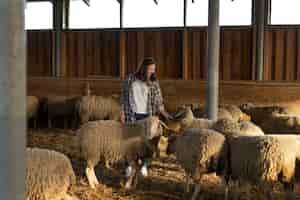 Foto gratuita donna a tutto campo che si prende cura delle pecore