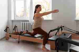 Free photo full shot woman taking  pilates reformer class