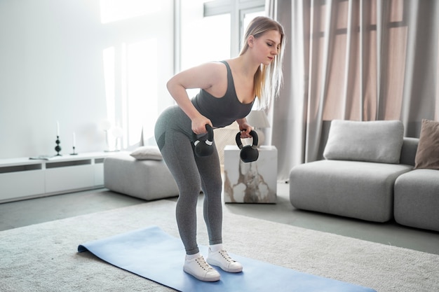 Full shot woman training with kettlebells