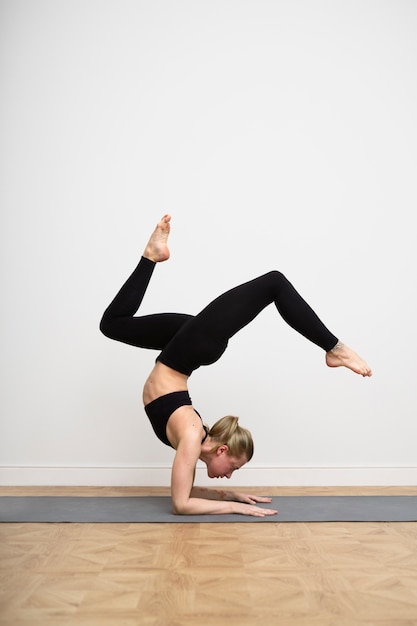 Foto gratuita donna a tutto campo che si allena sul tappetino da yoga