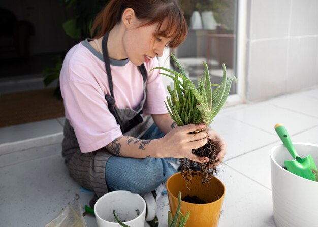 Full shot woman transplanting plant