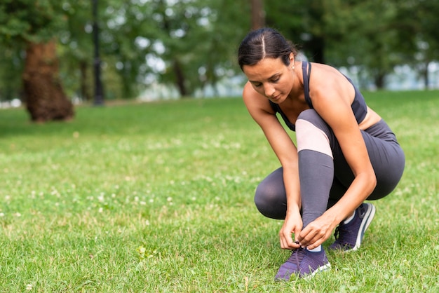 Full shot woman tying her shoelaces