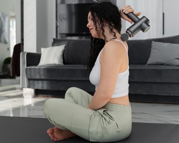 Full shot woman using massage gun