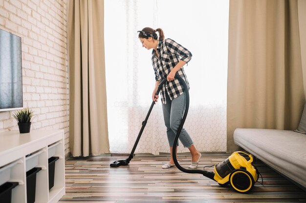 Full shot woman vacuuming in living room