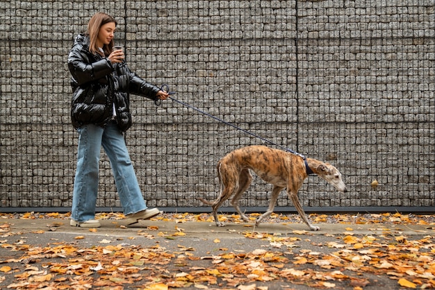 Full shot woman walking dog outdoors