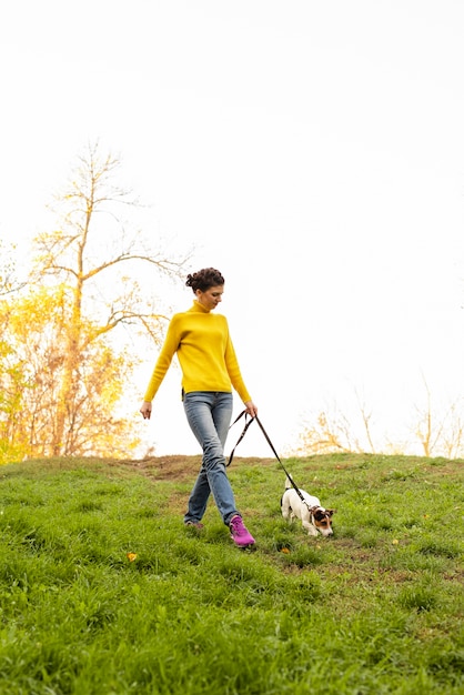 Полная выстрел женщина гуляет со своей собакой в парке